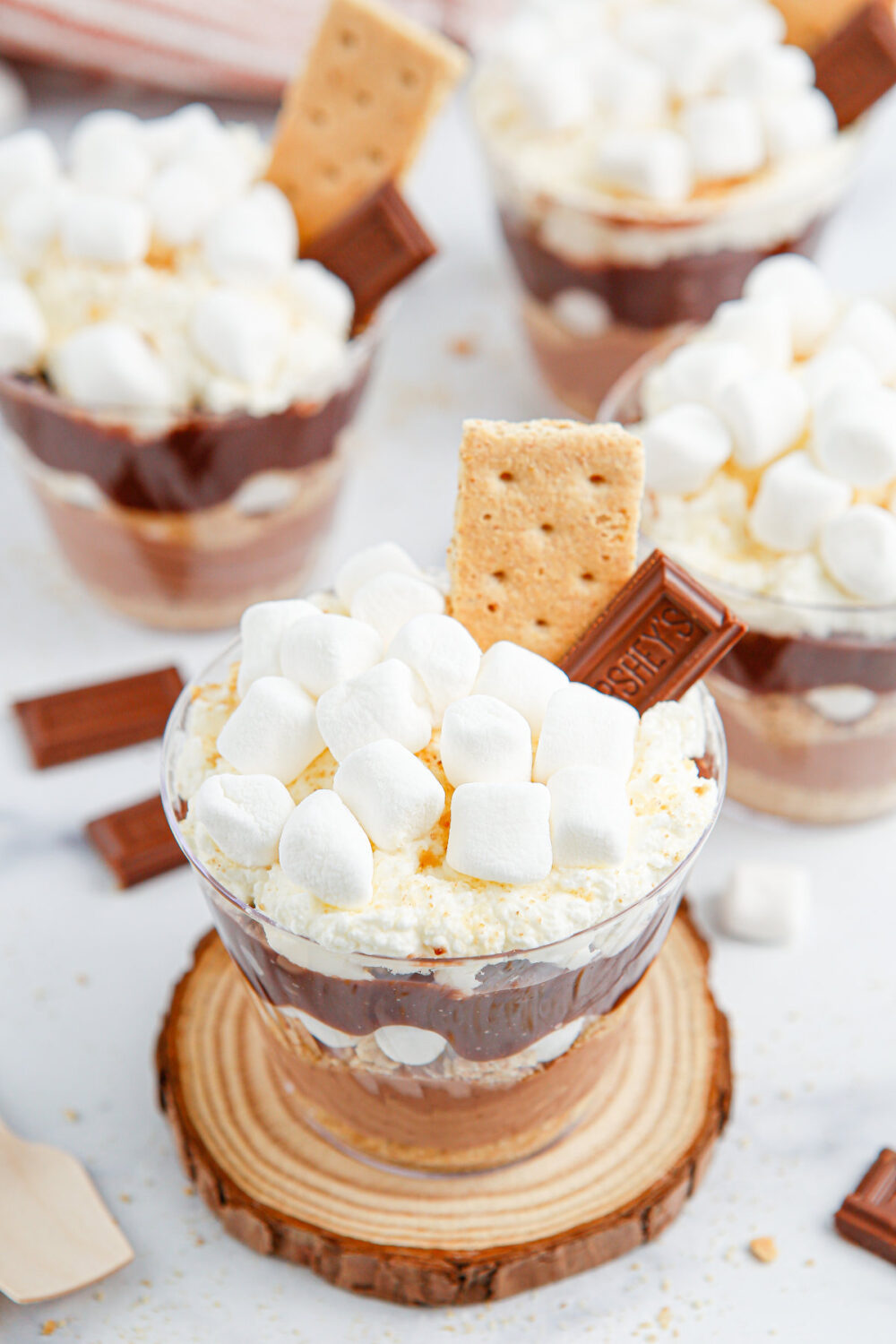 Pudding desserts topped with marshmallows, chocolate, and graham crackers. 