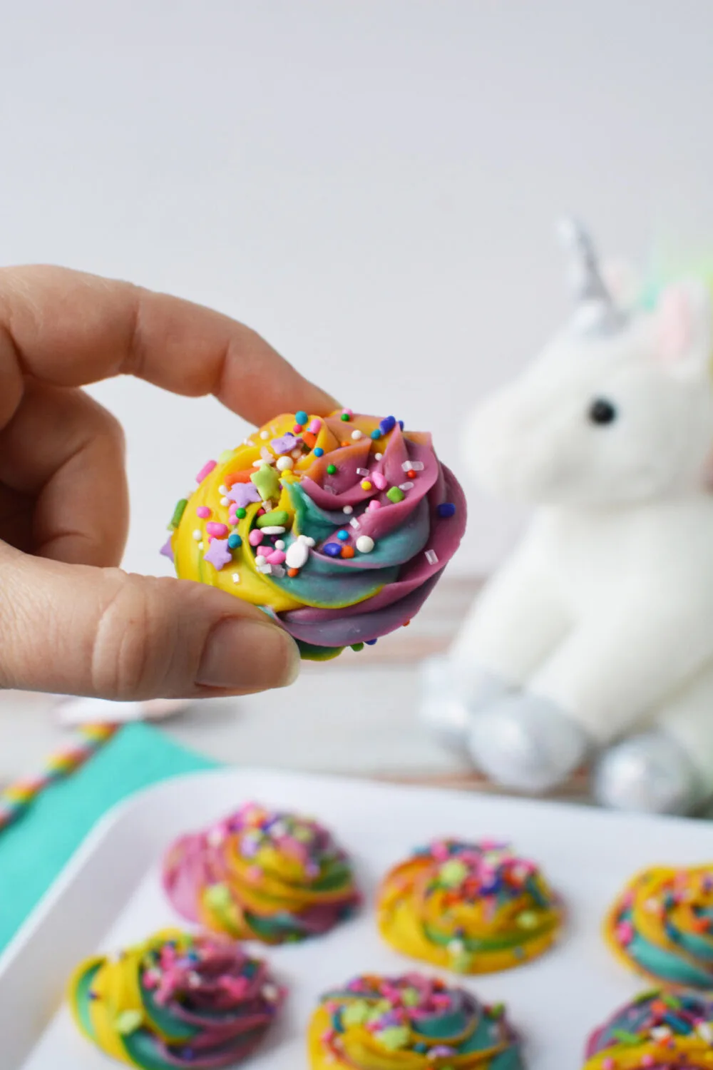 Holding a piece of swirled rainbow fudge with sprinkles. 