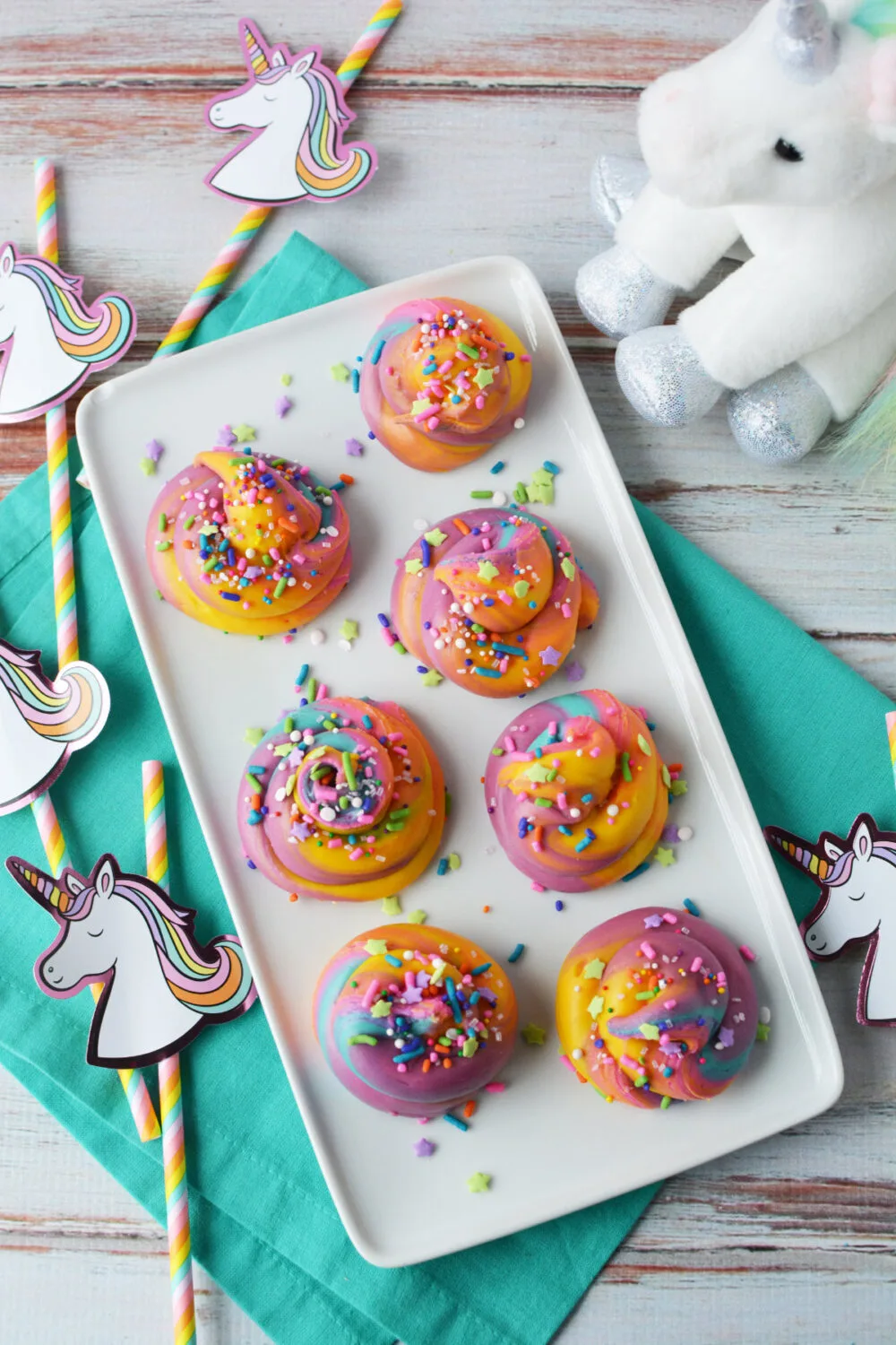 Tray of swirled rainbow fudge next to unicorn party favors. 