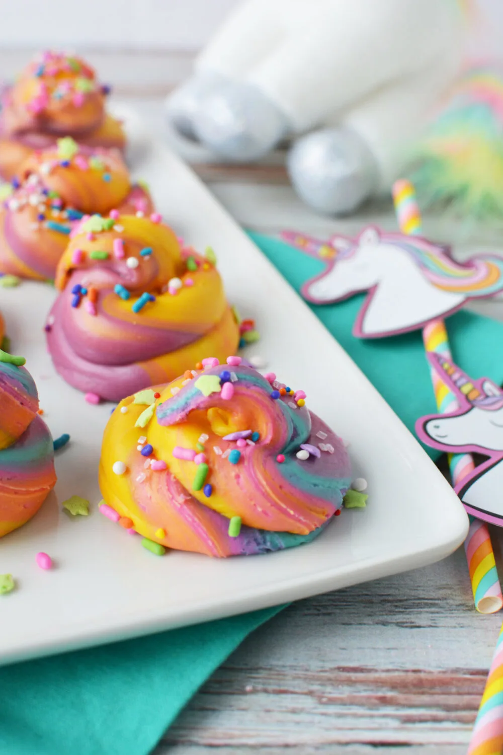 Unicorn rainbow poop fudge on a tray next to paper party favors. 