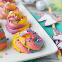 Unicorn rainbow poop fudge on a tray next to paper party favors.