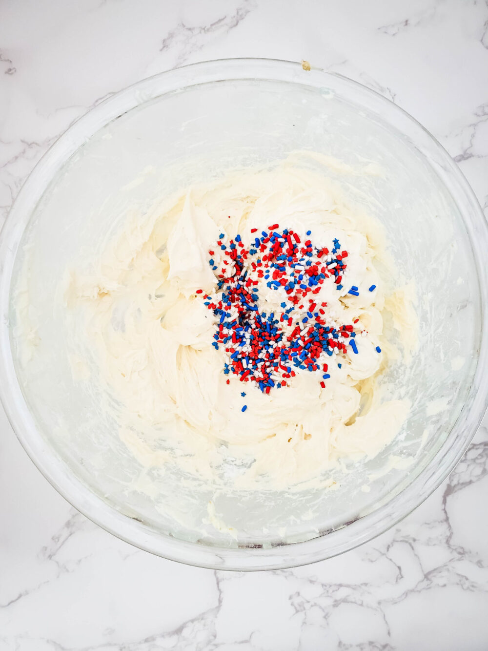 Cream cheese and sprinkles being mixed in a bowl. 
