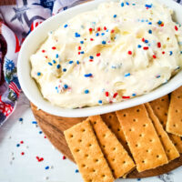 Cheesecake dip with red, white, and blue sprinkles, and graham crackers for dipping.