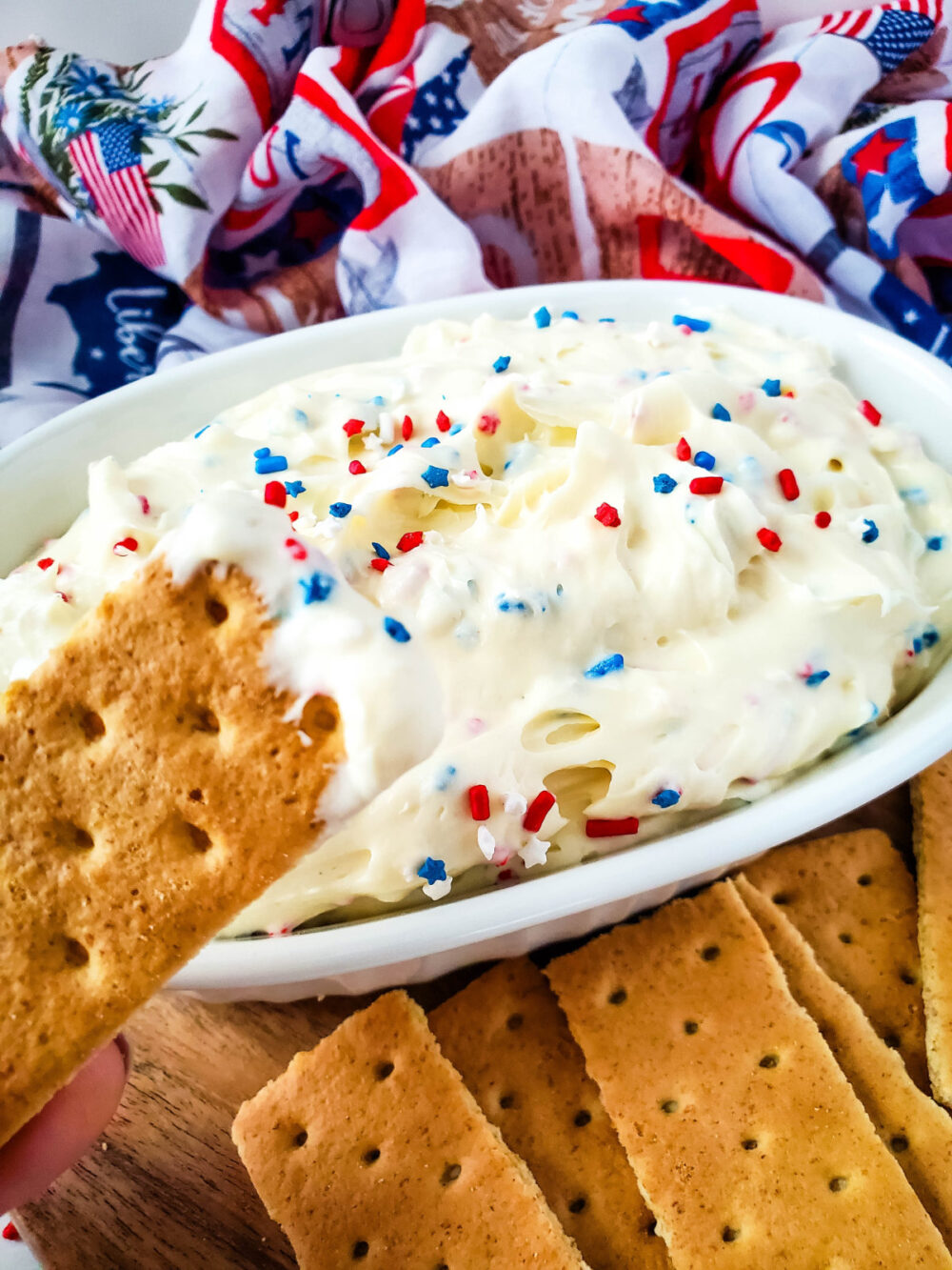 Dipping a graham cracker into red, white, and blue cheesecake dip. 