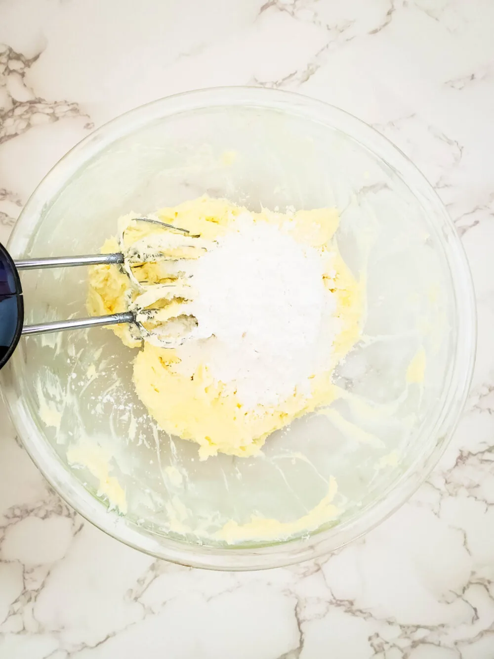 Powdered sugar and butter in a mixing bowl. 