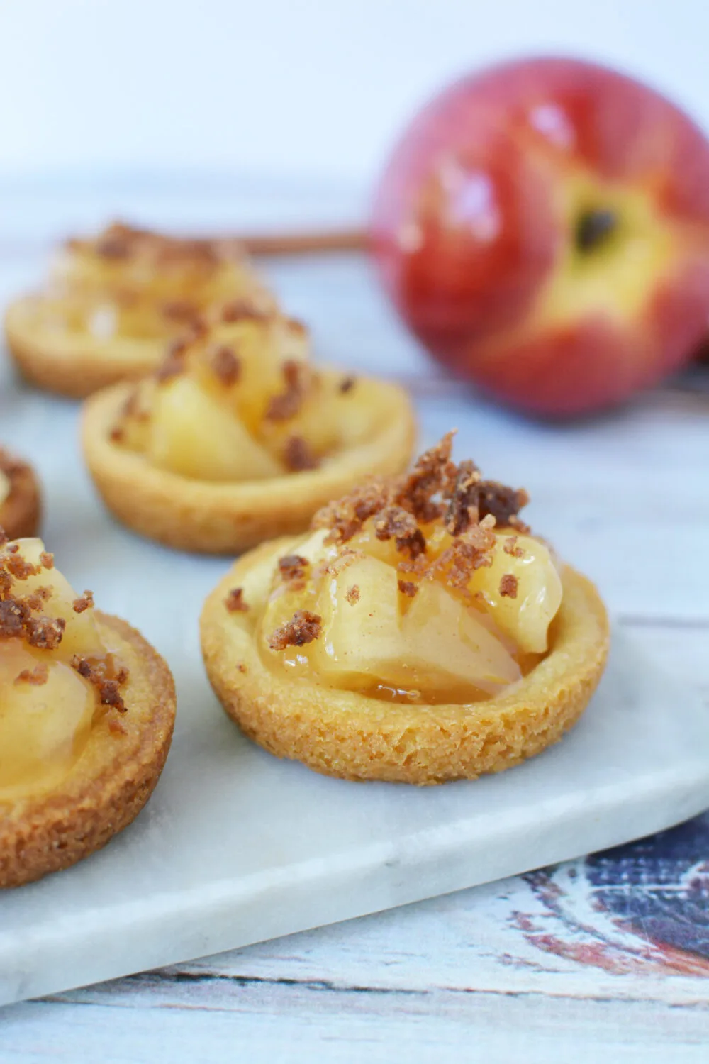 Apple pie cookies on a board next to a red apple. 