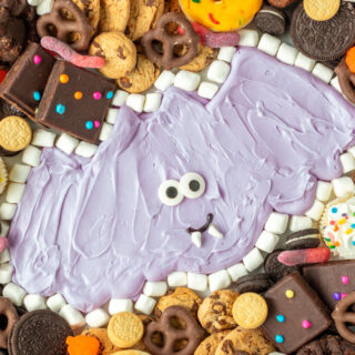 Purple frosting bat surrounded by sweets and treats for a Halloween buttercream board.