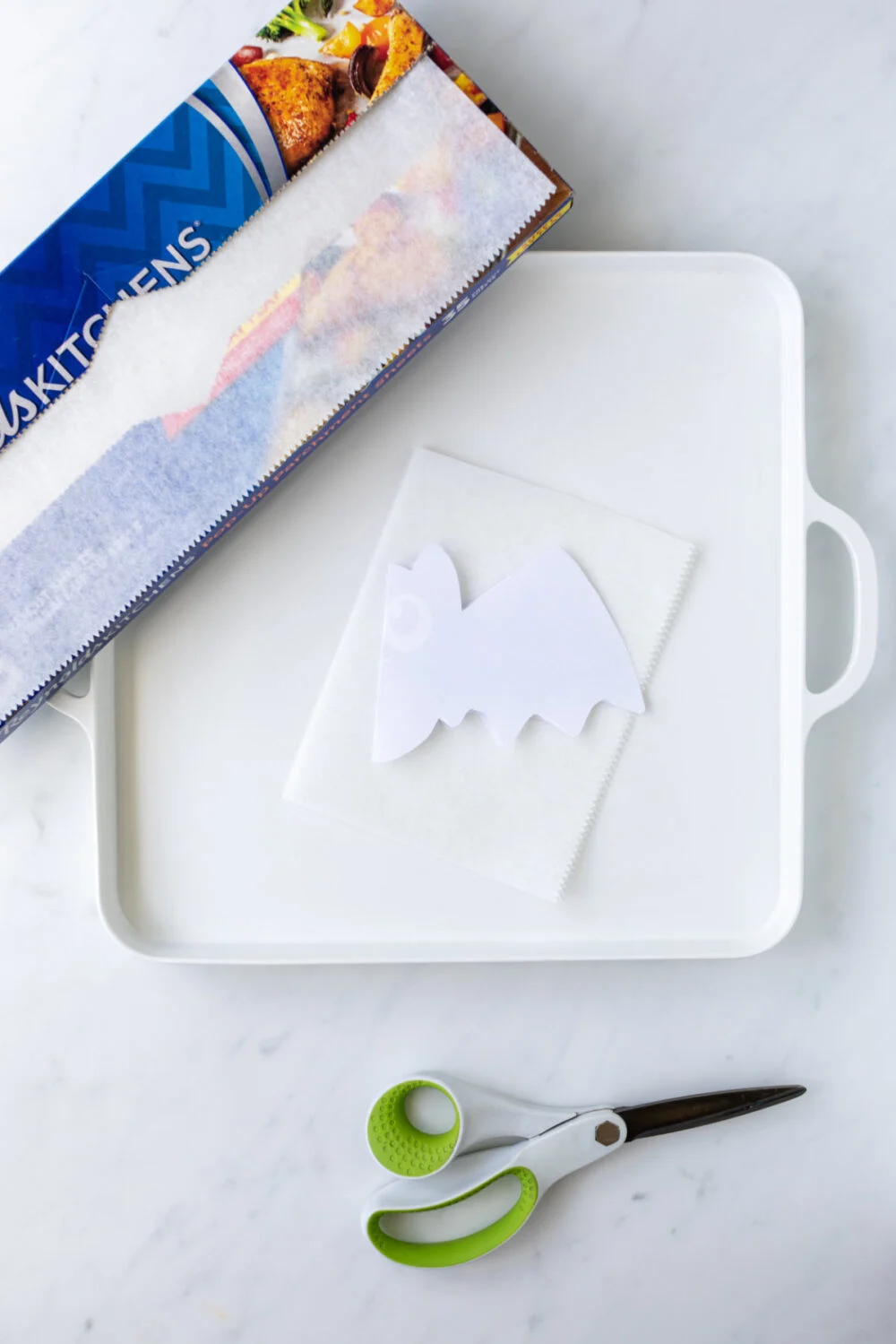Bat template on a plate with parchment paper and scissors. 