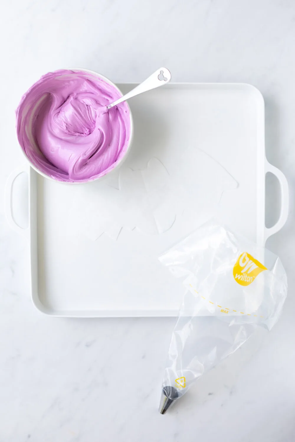 Purple frosting next to a bat template and piping bag. 