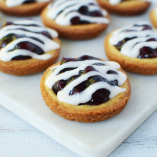 Blueberry pie cookies with glaze on a white tray.