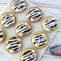 Glazed blueberry pie cookies on a white tray.