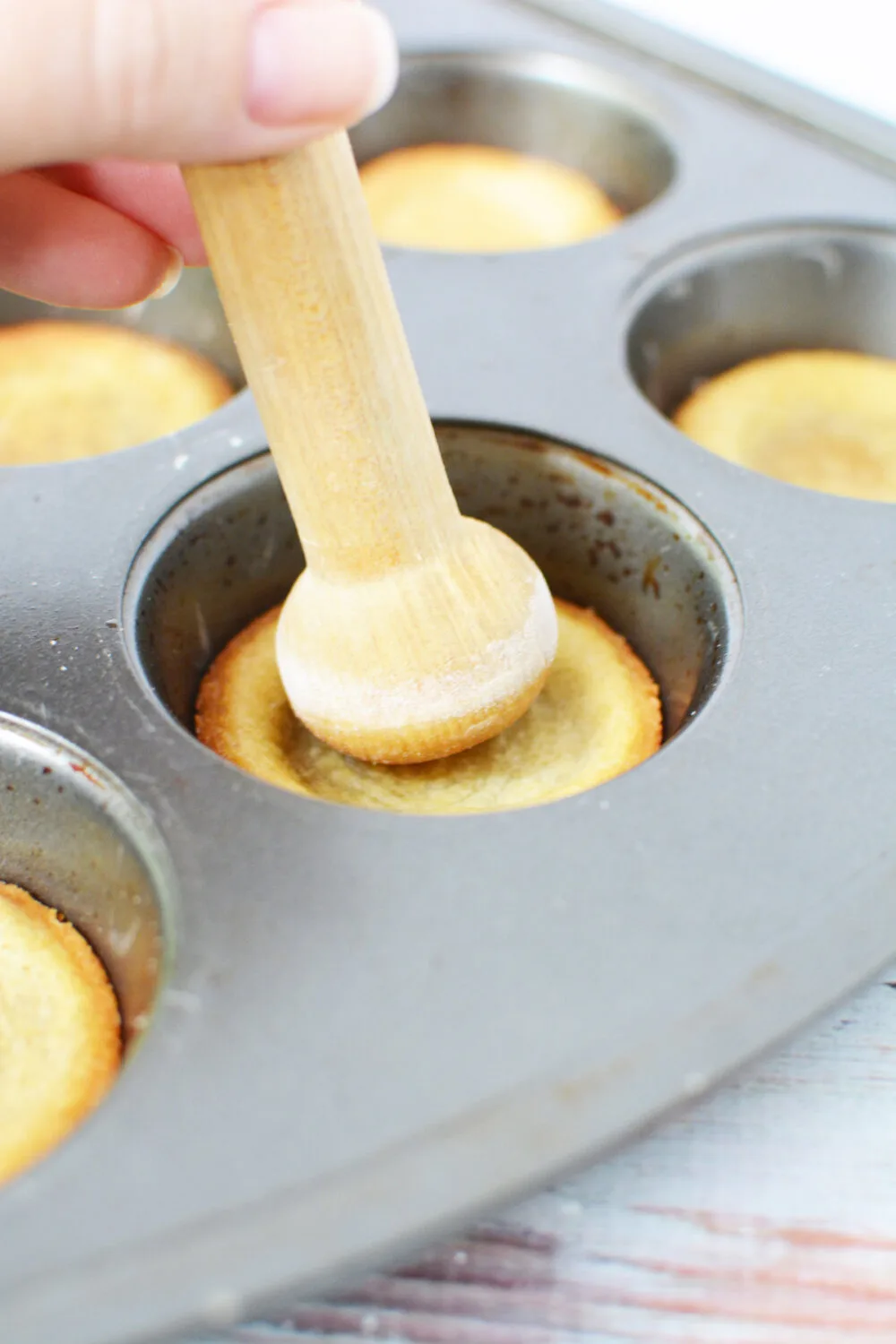 Using a tart shaper to shape baked cookies. 
