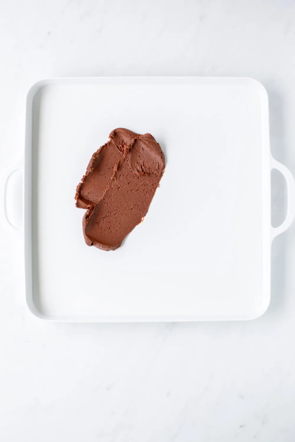 Chocolate frosting on a square serving tray. 
