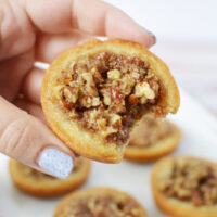 Holding a pecan pie sugar cookie with a bite missing.