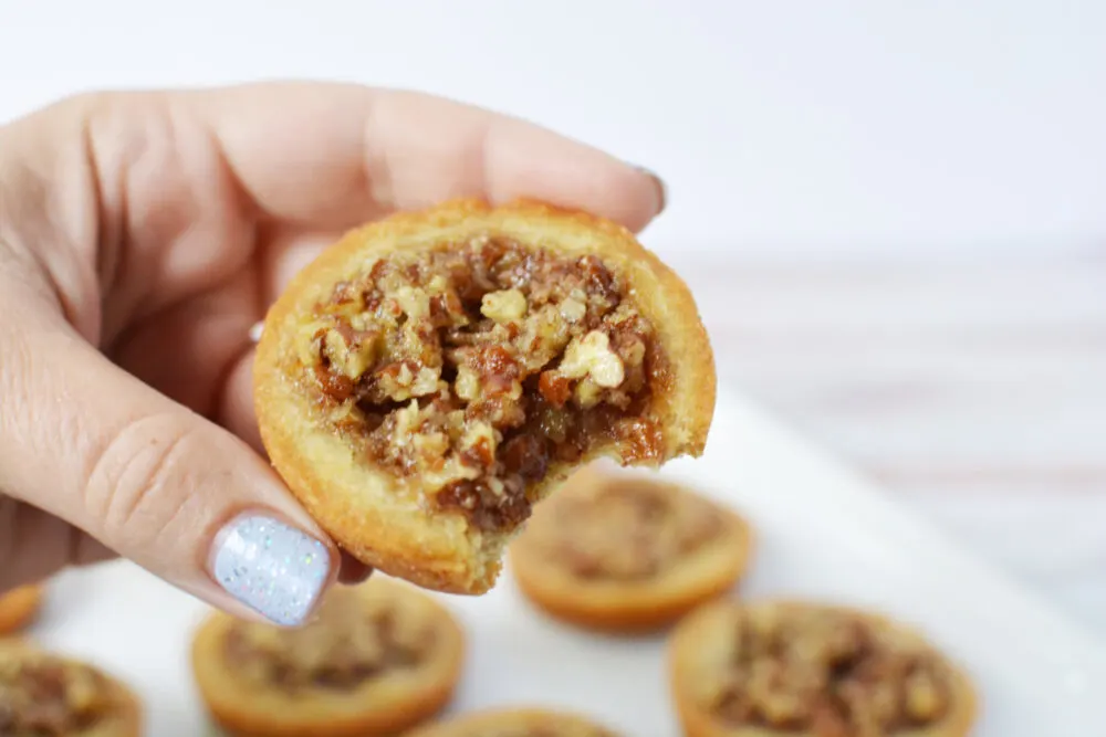 Holding a pecan pie cookie with a bite taken out of it. 