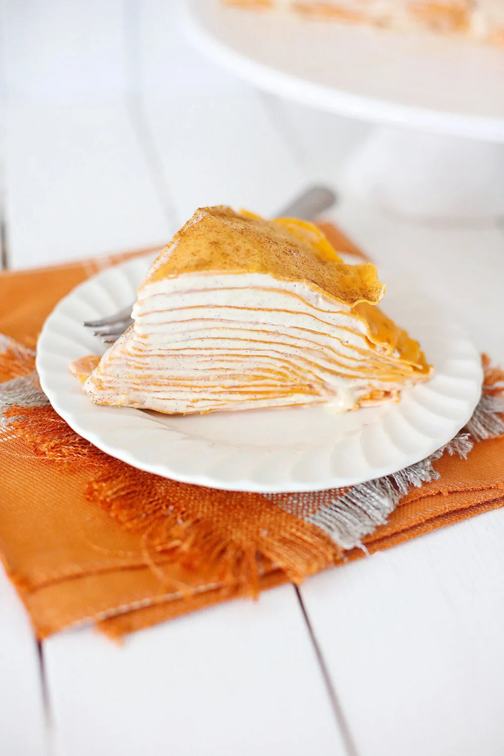 Slice of pumpkin spice crepe cake on a plate. 