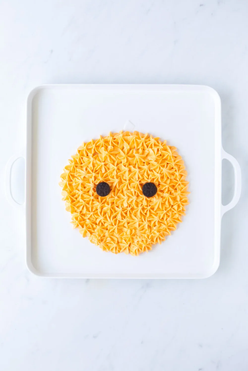 Adding cookie eyes to the frosting pumpkin. 