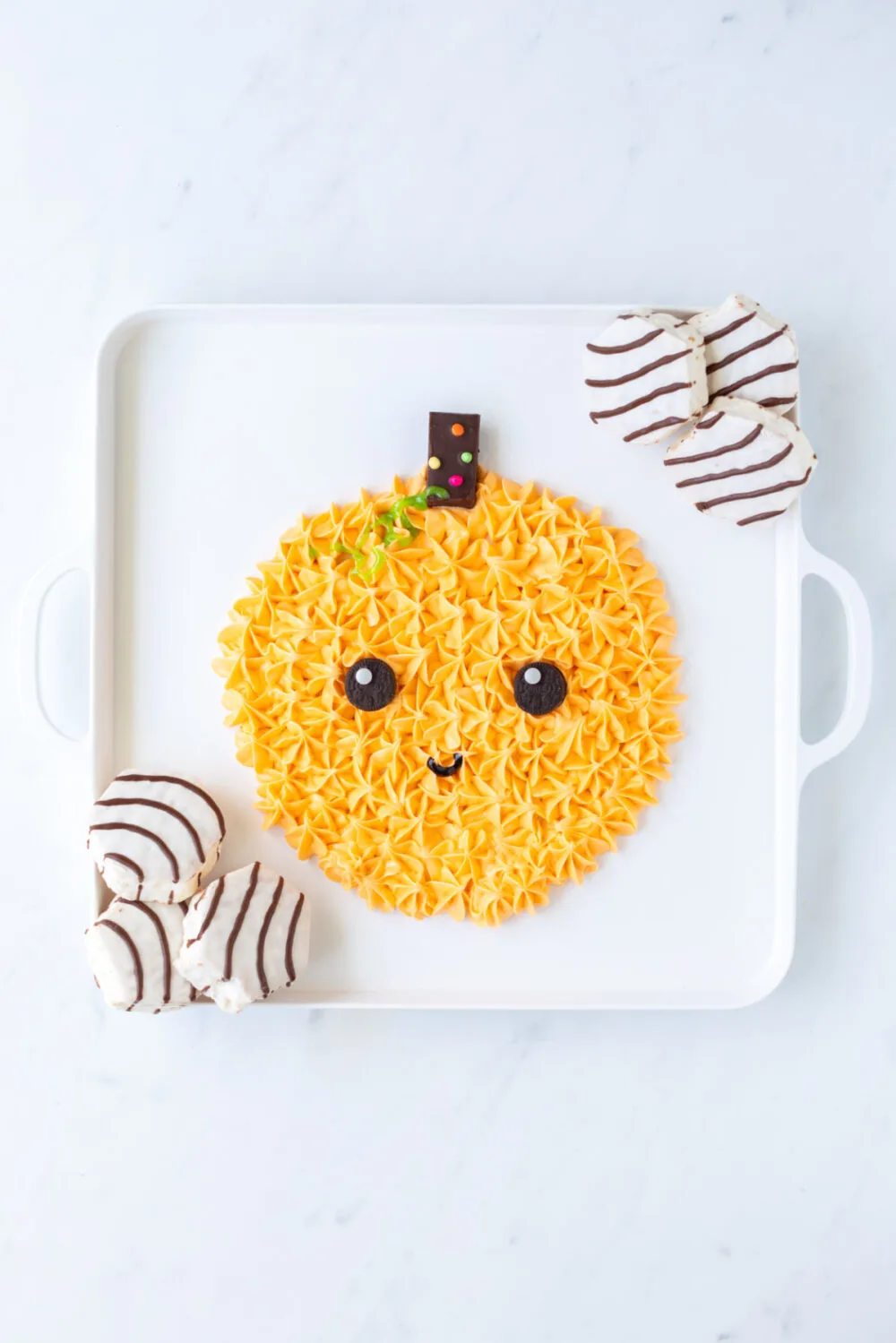 Cute smiling pumpkin made out of frosting on a board with Zebra cakes. 