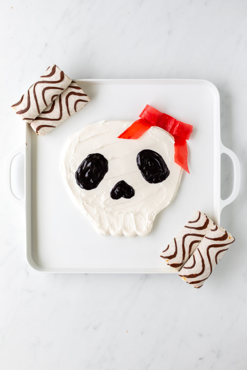 Zebra cakes at the corners of the frosting skull board. 
