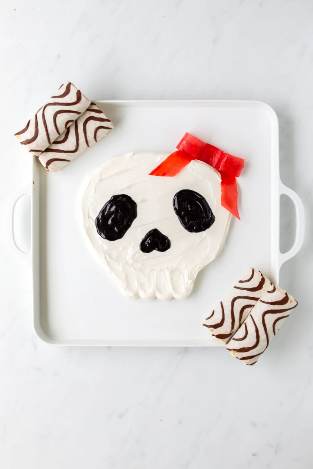 Zebra cakes at the corners of the frosting skull board. 