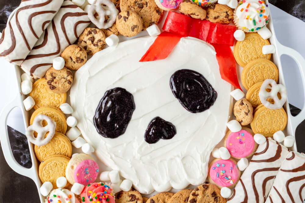 Skull frosting board surrounded by cookies and candies. 