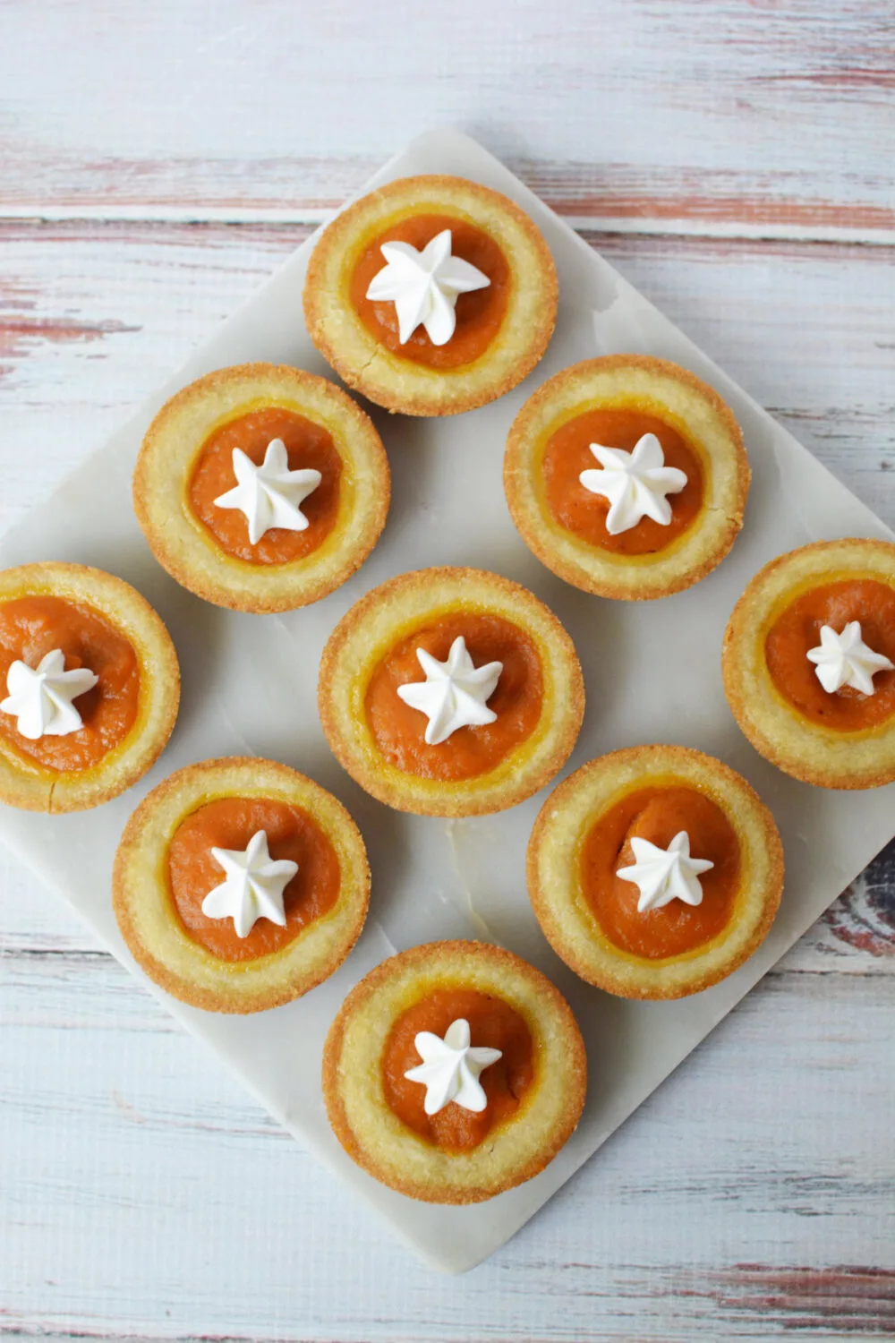 Mini pumpkin pies in sugar cookie crusts with whipped cream toppings.