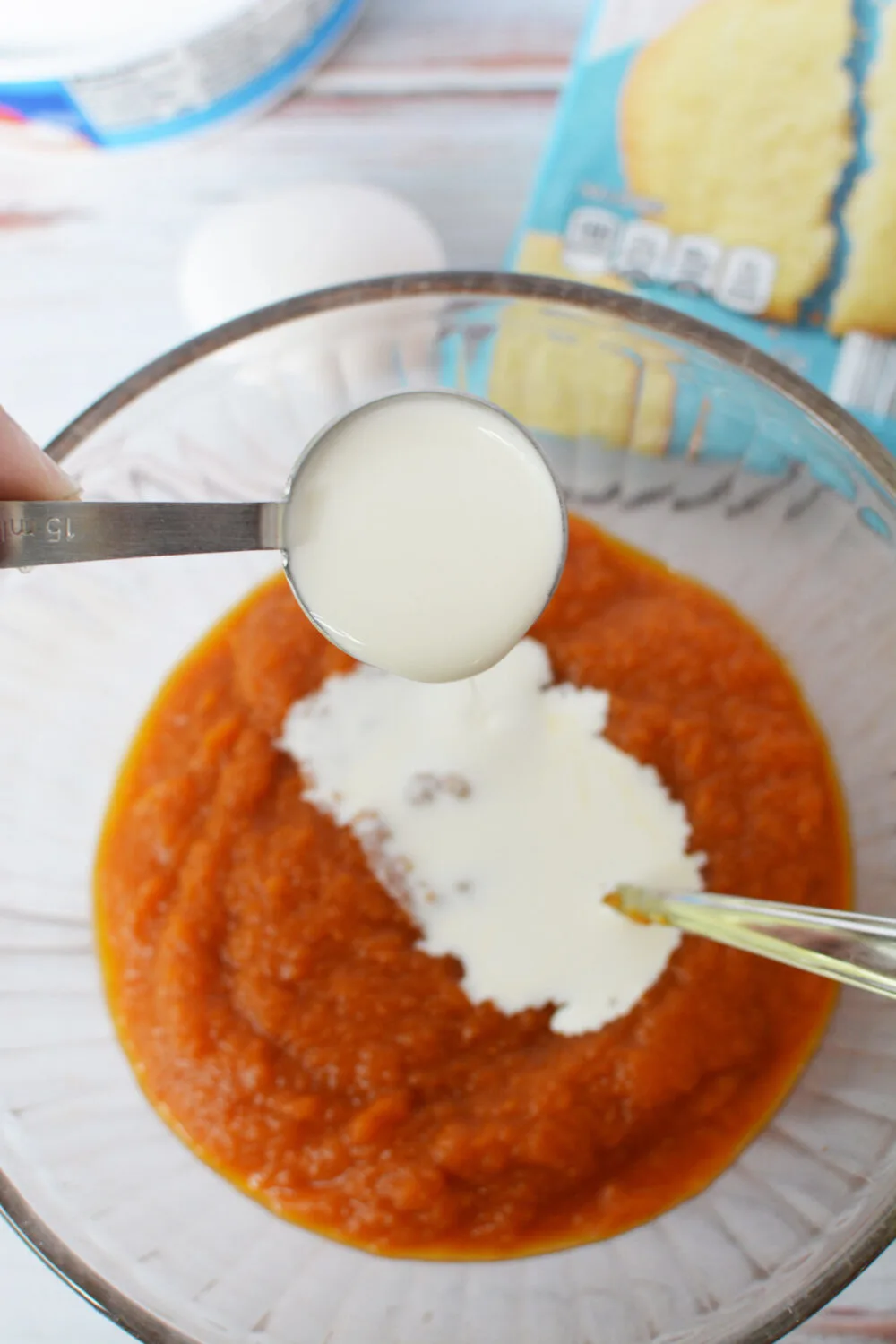 Heavy cream pouring into pumpkin pie filling.