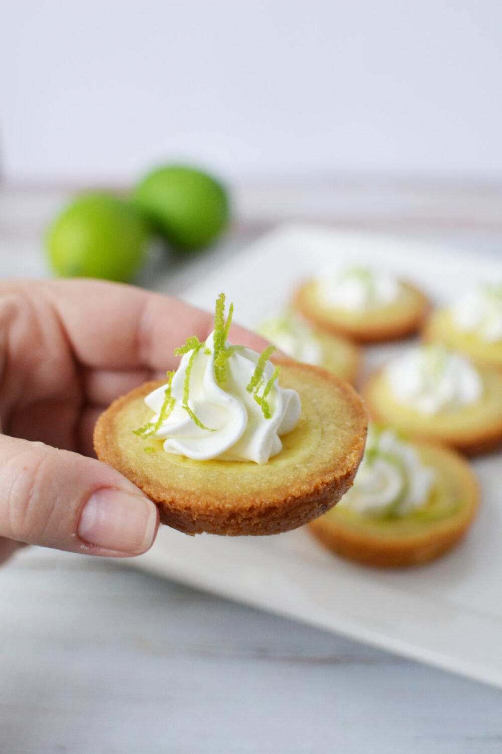 Holding a key lime pie cookie with topping. 