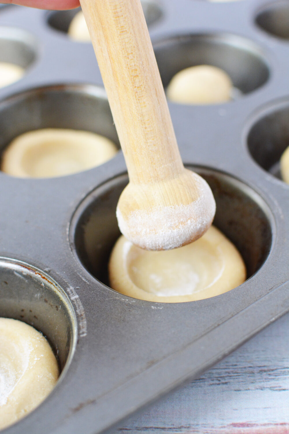 Flour-dipped tart shaper shaping cookie dough in a tin. 
