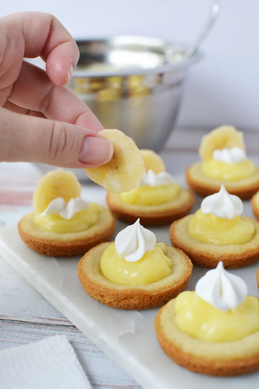 Adding banana slices to the tops of the banana cream cookies. 
