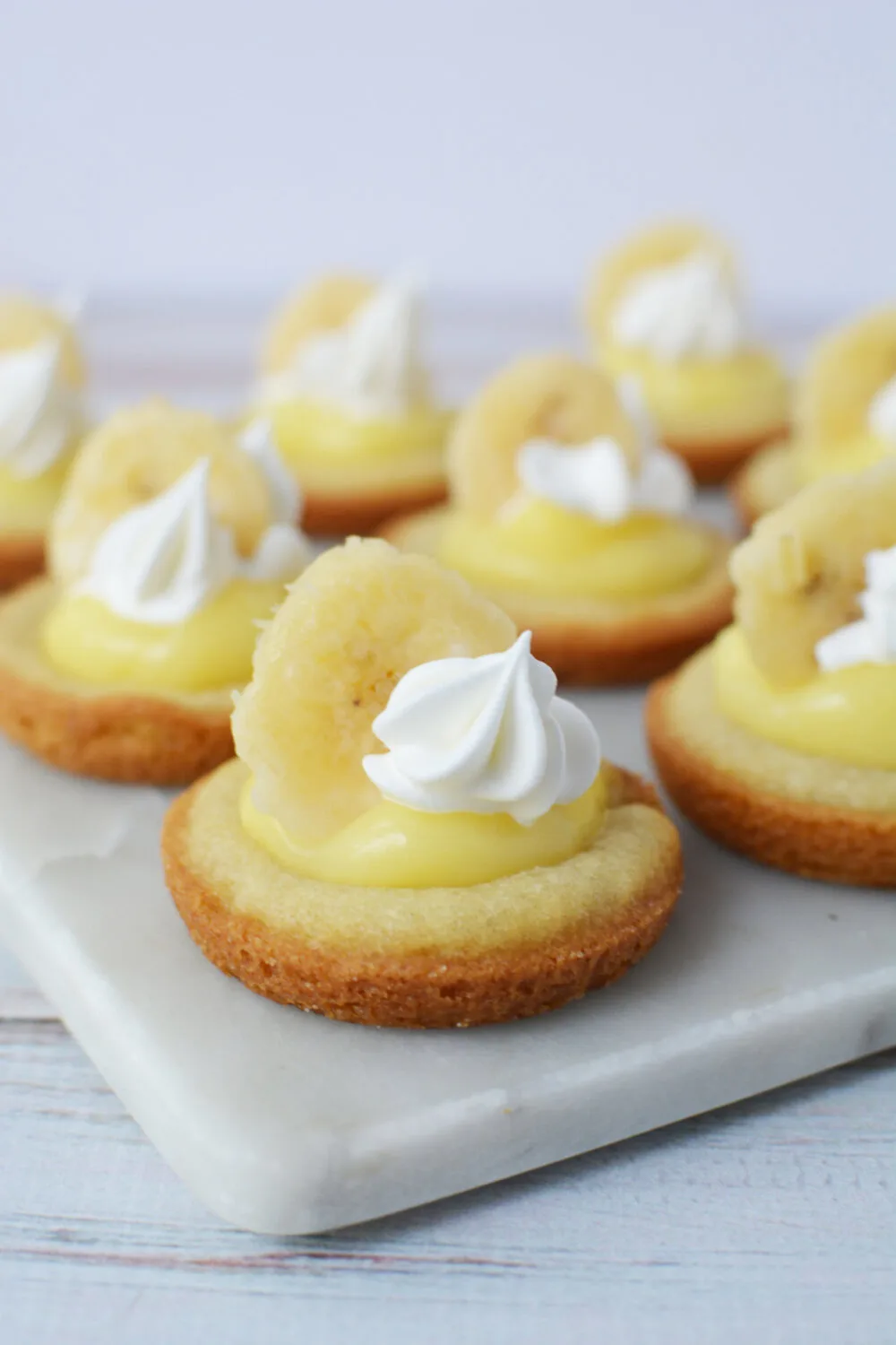 Banana cream pie cookies topped with whipped cream and fresh banana slices. 
