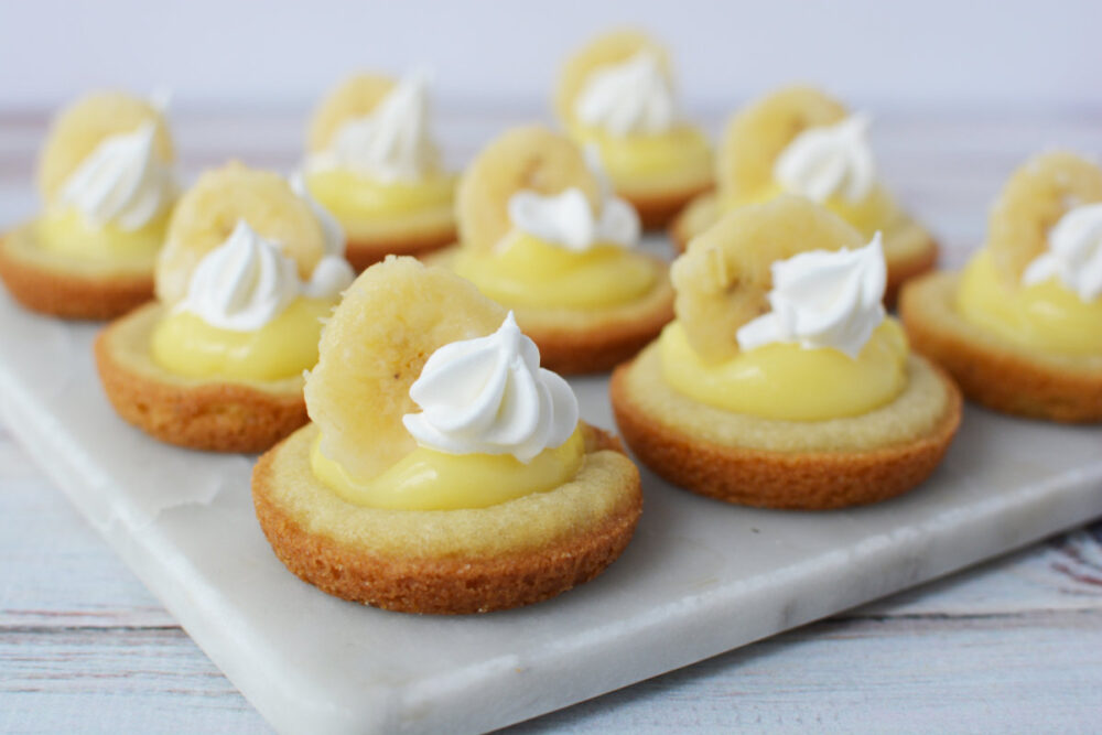 Banana cream pie cookies with sliced banana and whipped cream as toppings. 