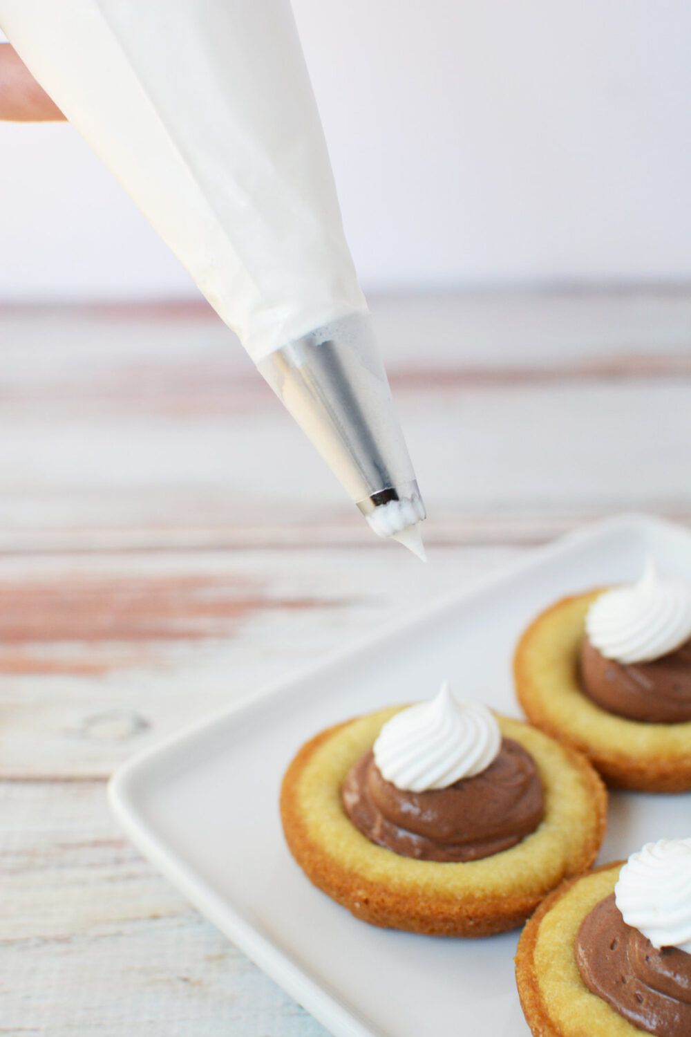 Piping whipped topping onto French silk pie cookies. 