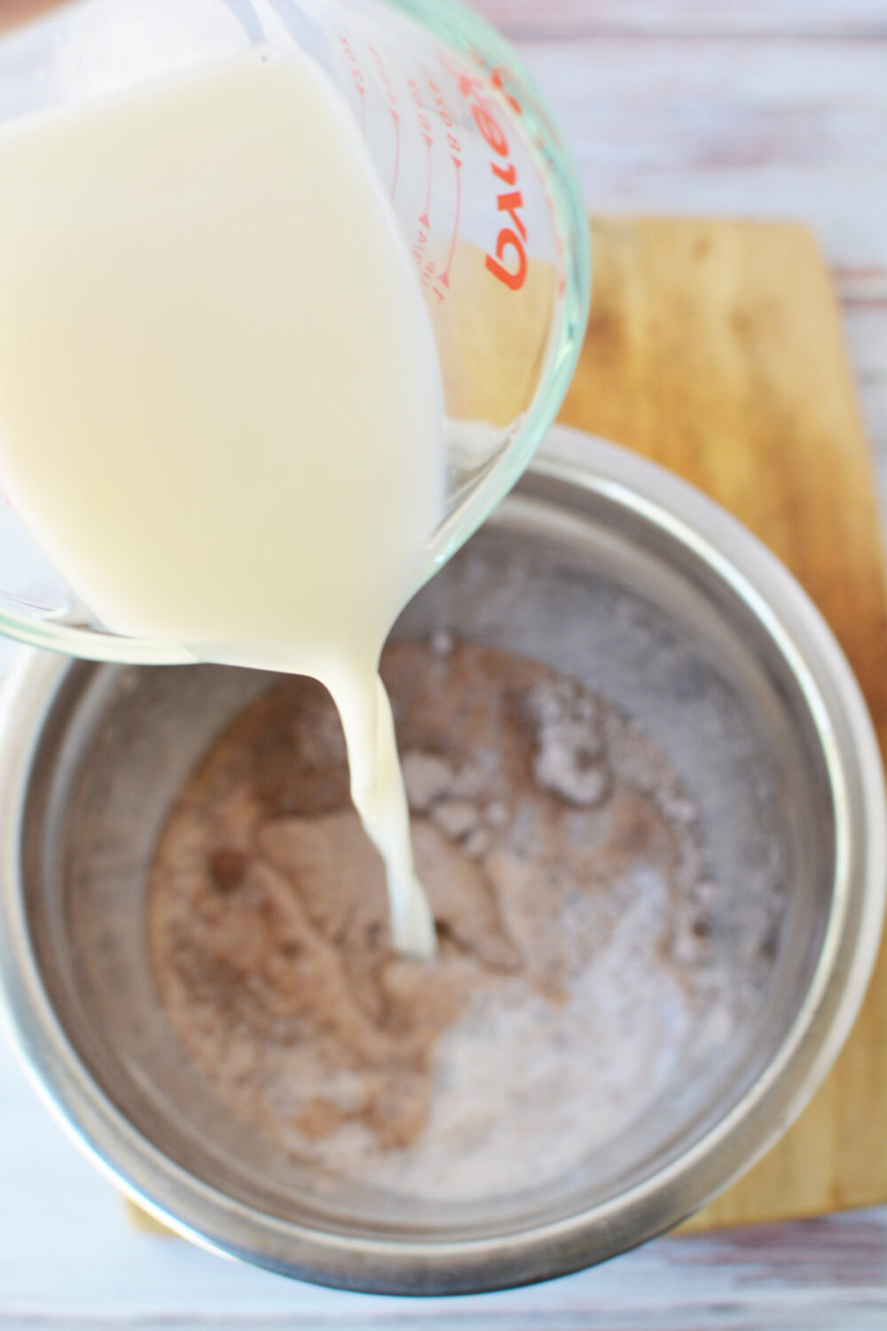 Pouring milk into chocolate pudding mix.