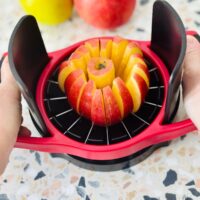 Using an apple slicer to cut a red apple.