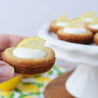 Holding a lemonade pie cookies with the tray in the background.