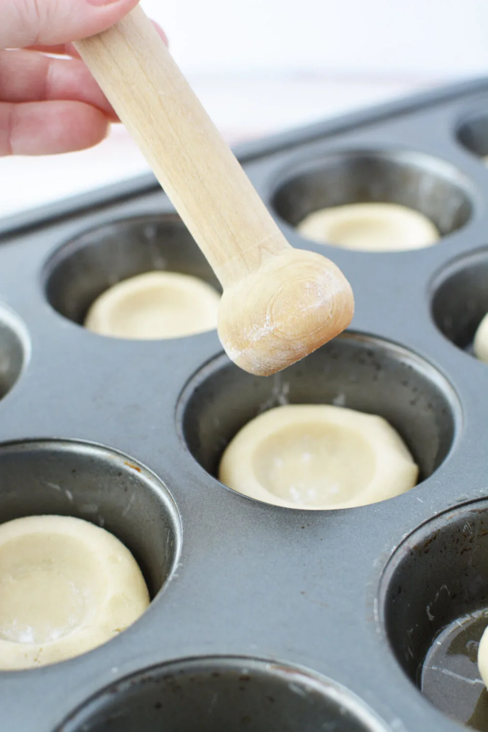 Using a tart shaper to shape dough in tins. 