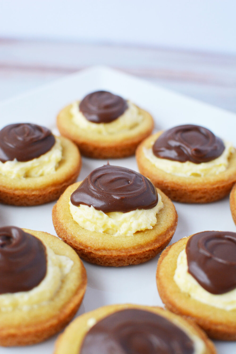Boston cream pie cookies topped with chocolate ganache on a plate.