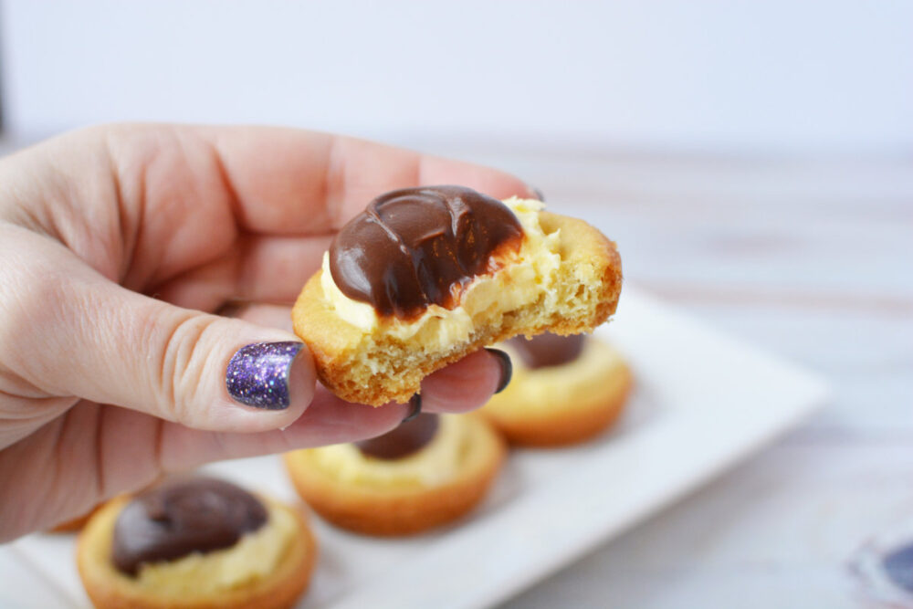 Holding a Boston cream pie cookie with a bite missing.