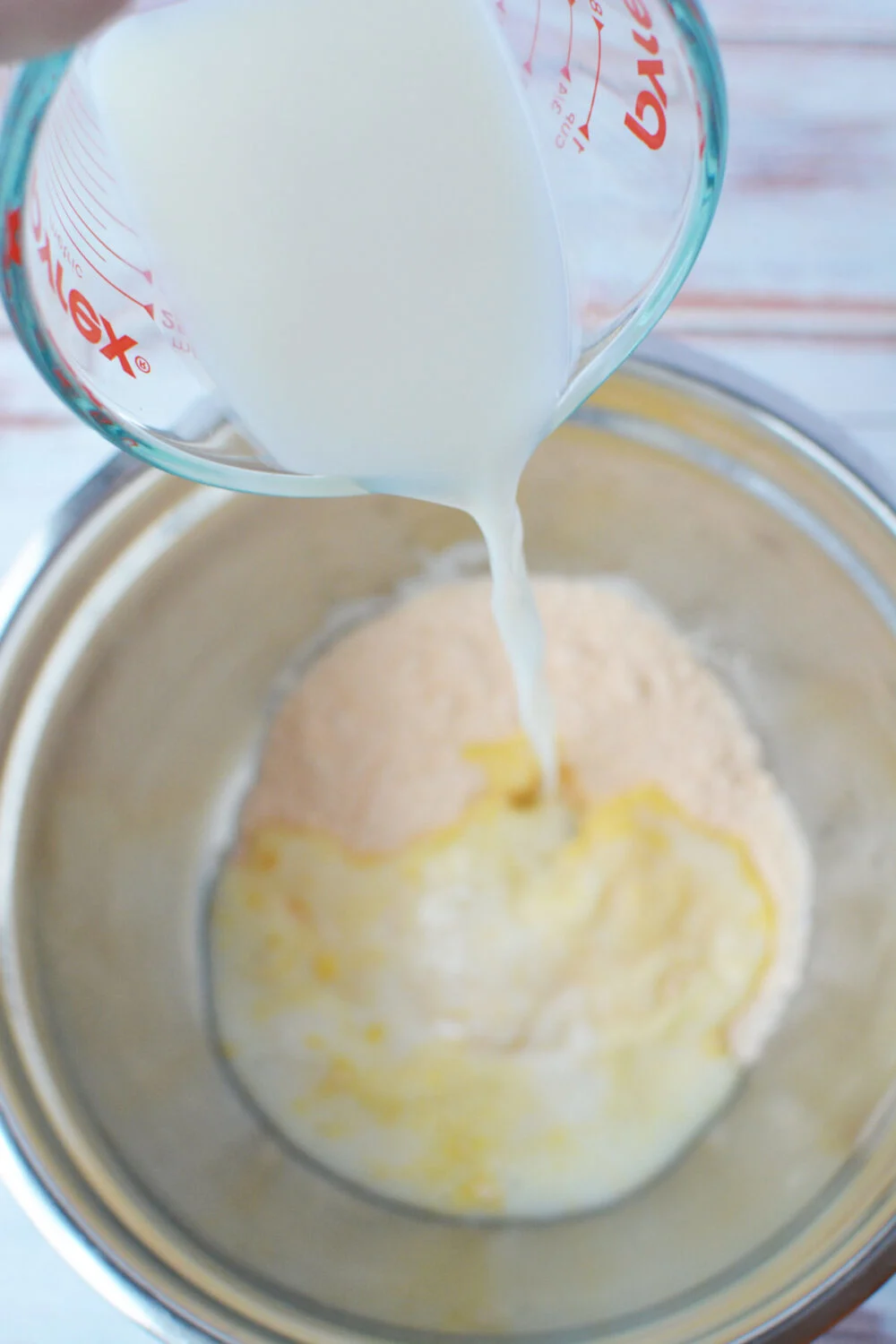 Pouring milk into vanilla pudding mix in a bowl. 