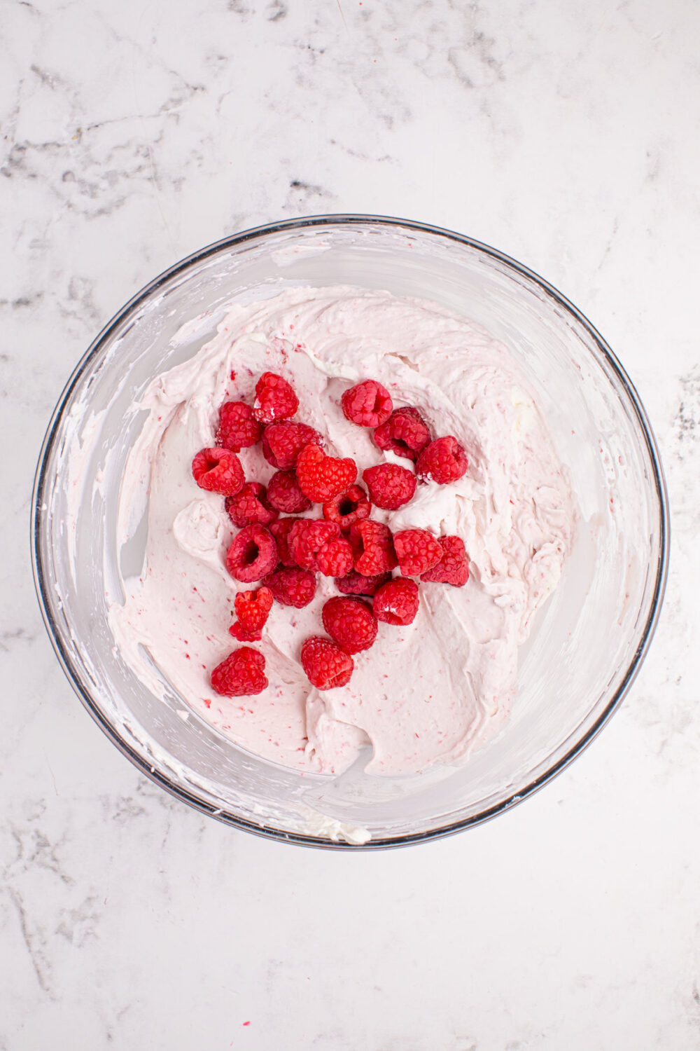 Fresh raspberries in a bowl with raspberry whipped cream mixture.
