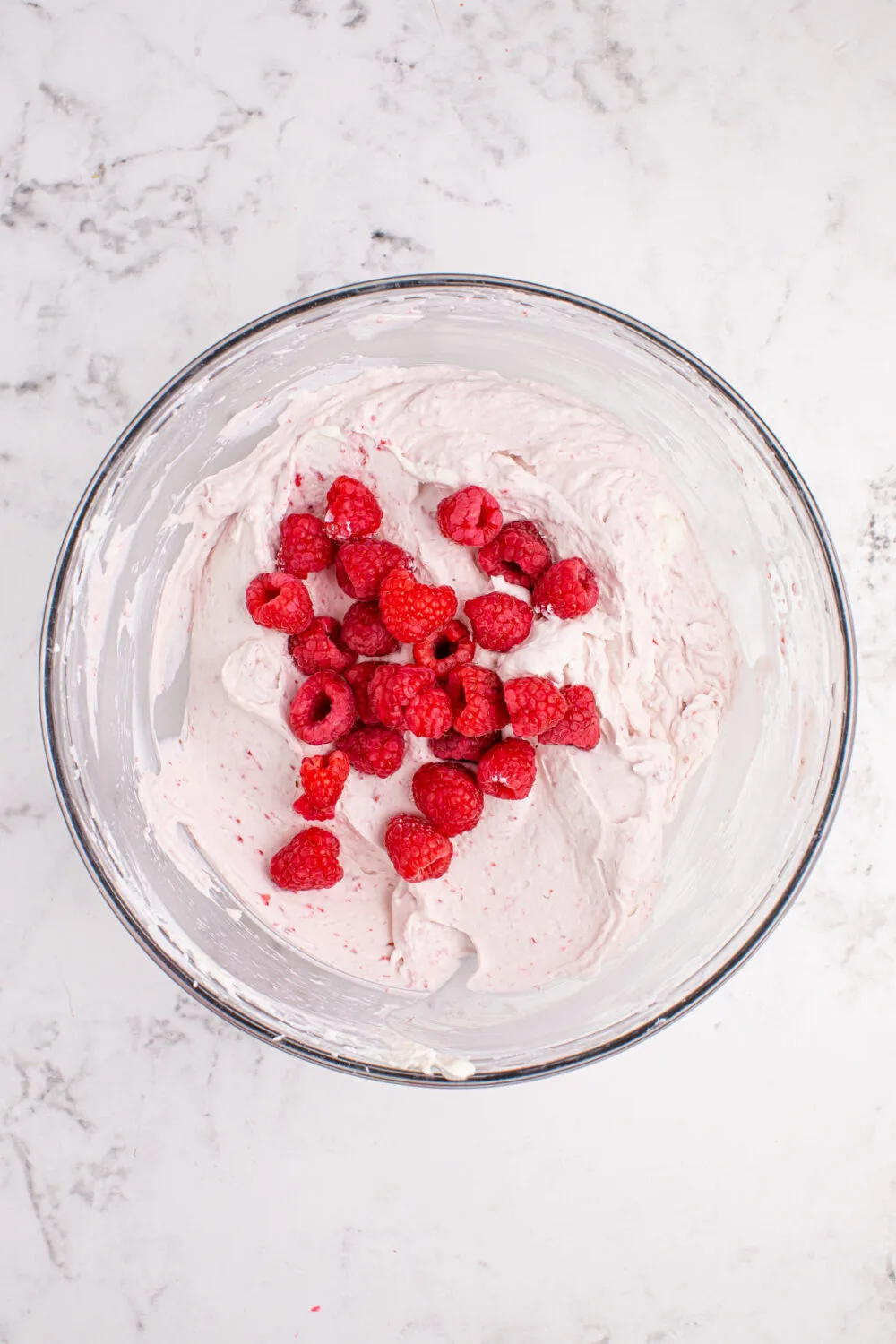 Fresh raspberries in a bowl with raspberry whipped cream mixture.