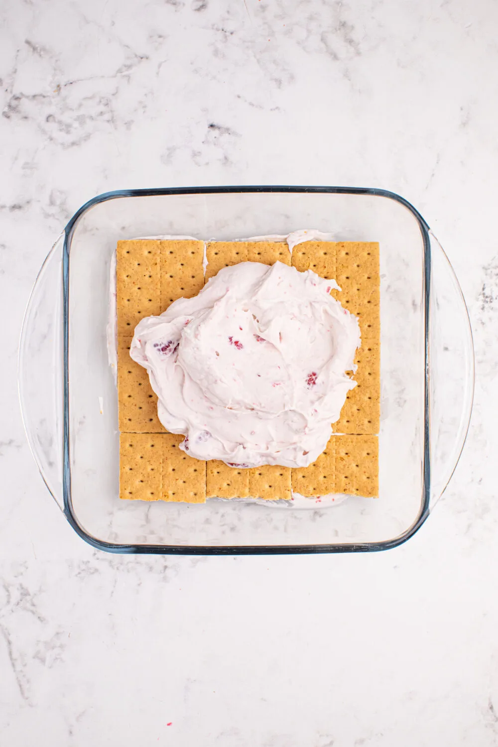 Next layer of raspberry whipped topping on top of graham crackers. 
