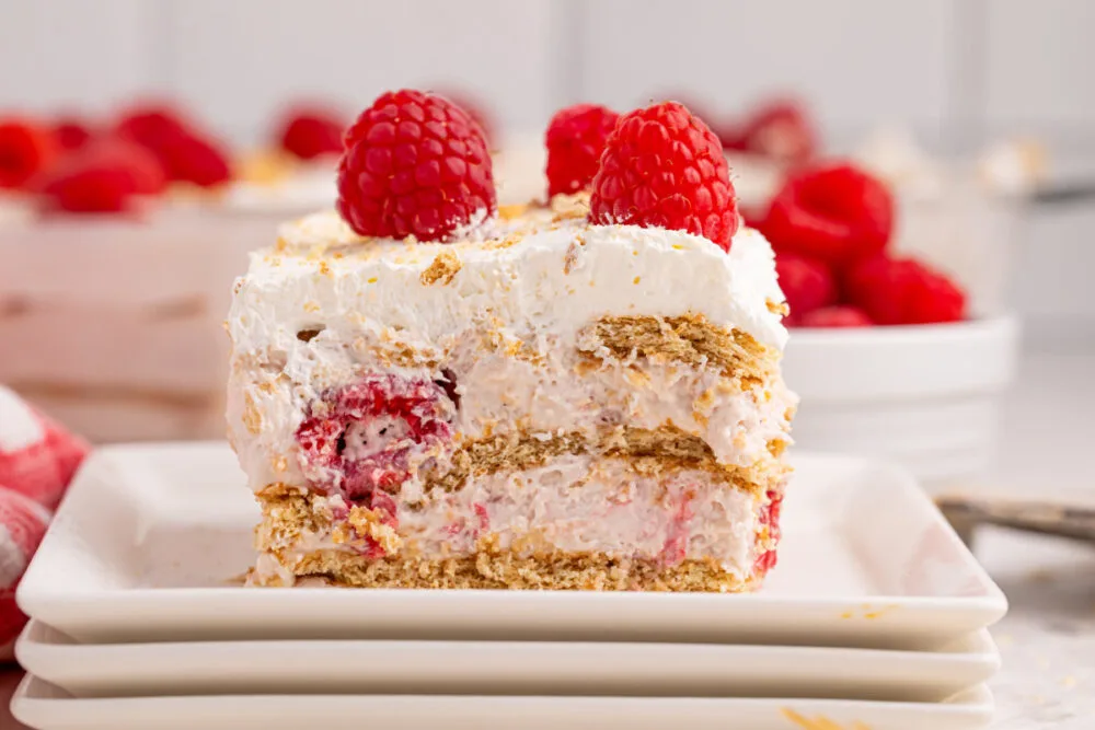 Raspberry icebox cake on a stack of white serving plates. 