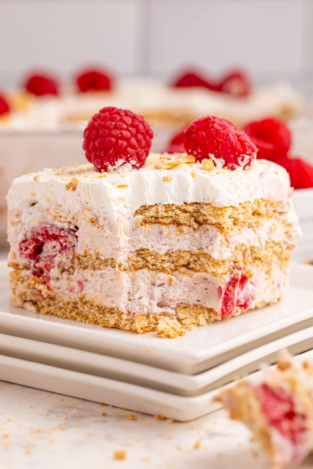 Slice of raspberry cream cake on a plate with a fork bite missing from it. 