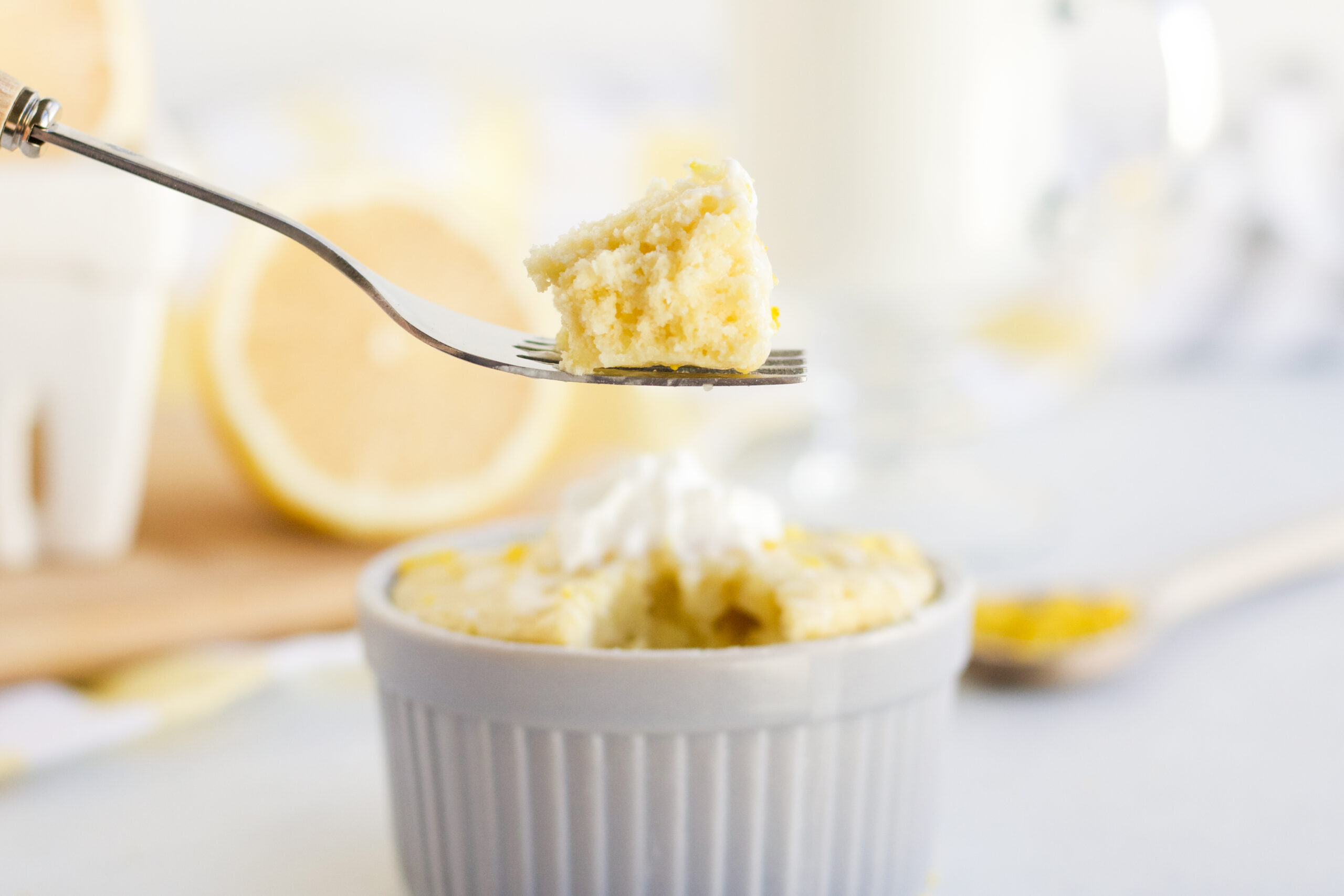 Lemon mug cake with a fork scooping a bite out. 