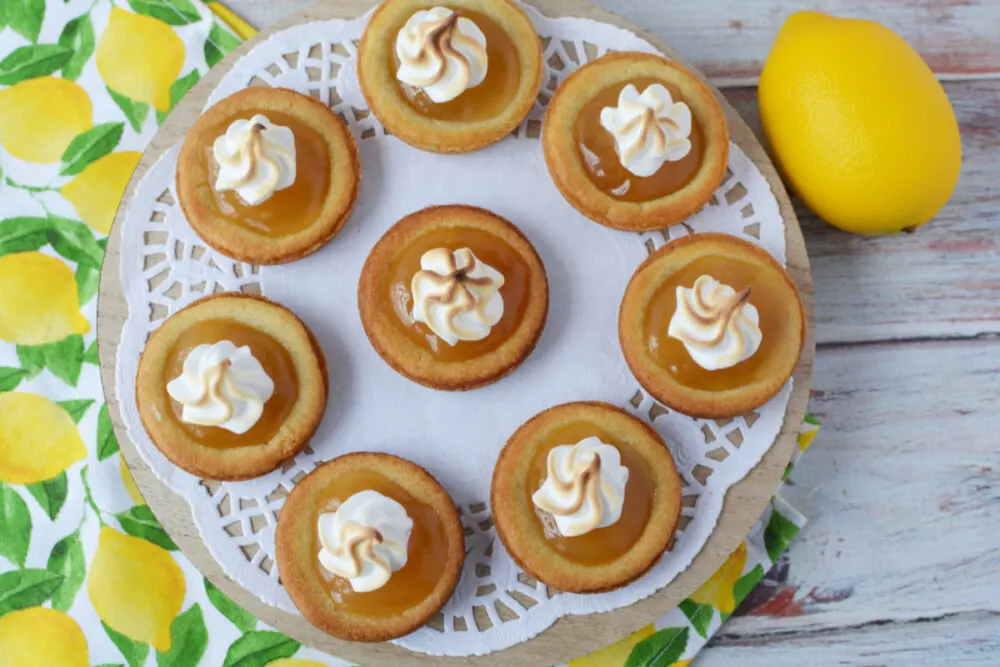 Lemon meringue cookies on a plate next to a lemon. 