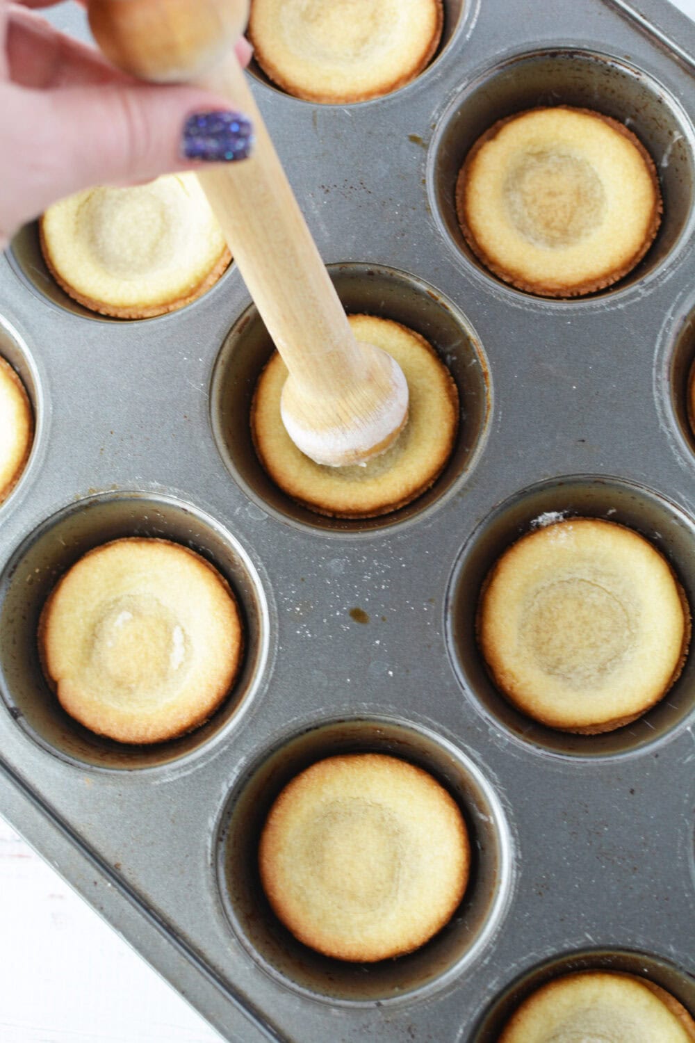 Using a tart shaper on baked sugar cookie crusts. 