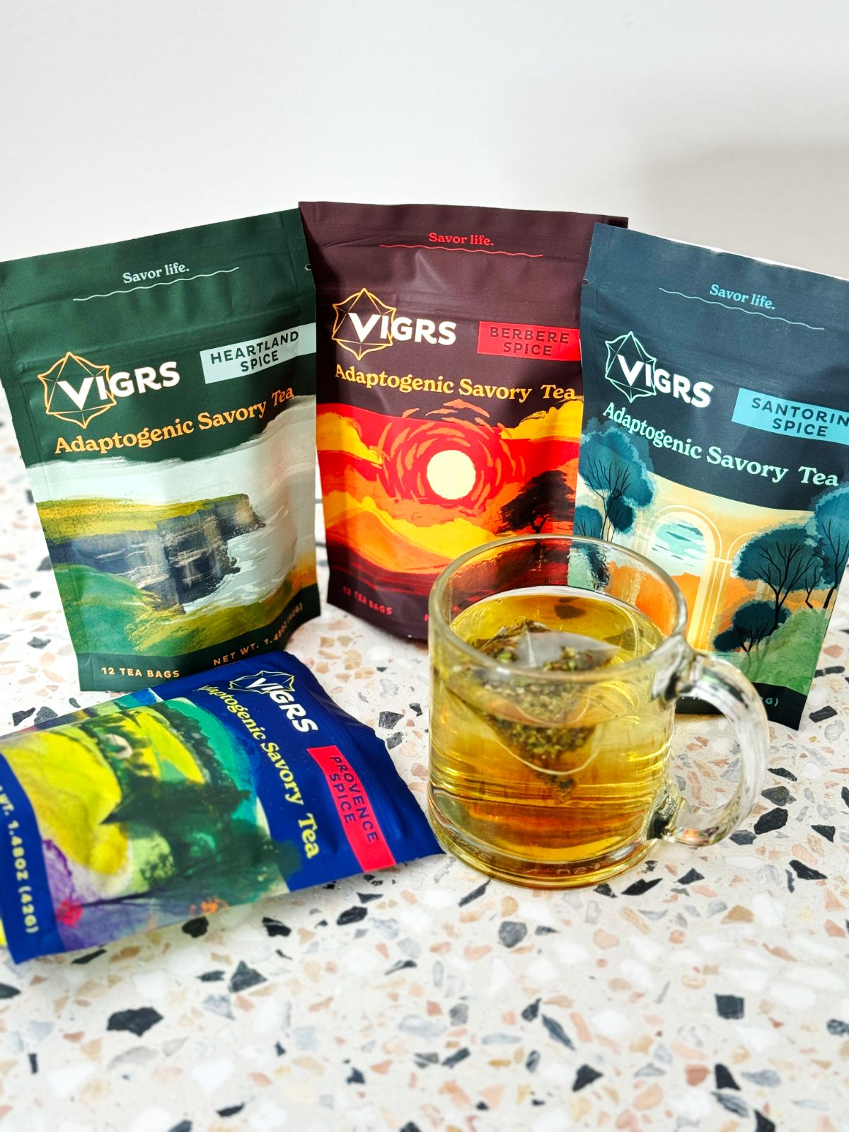Four bags of Vigrs savory tea and a tea bag steeping in a clear mug. 