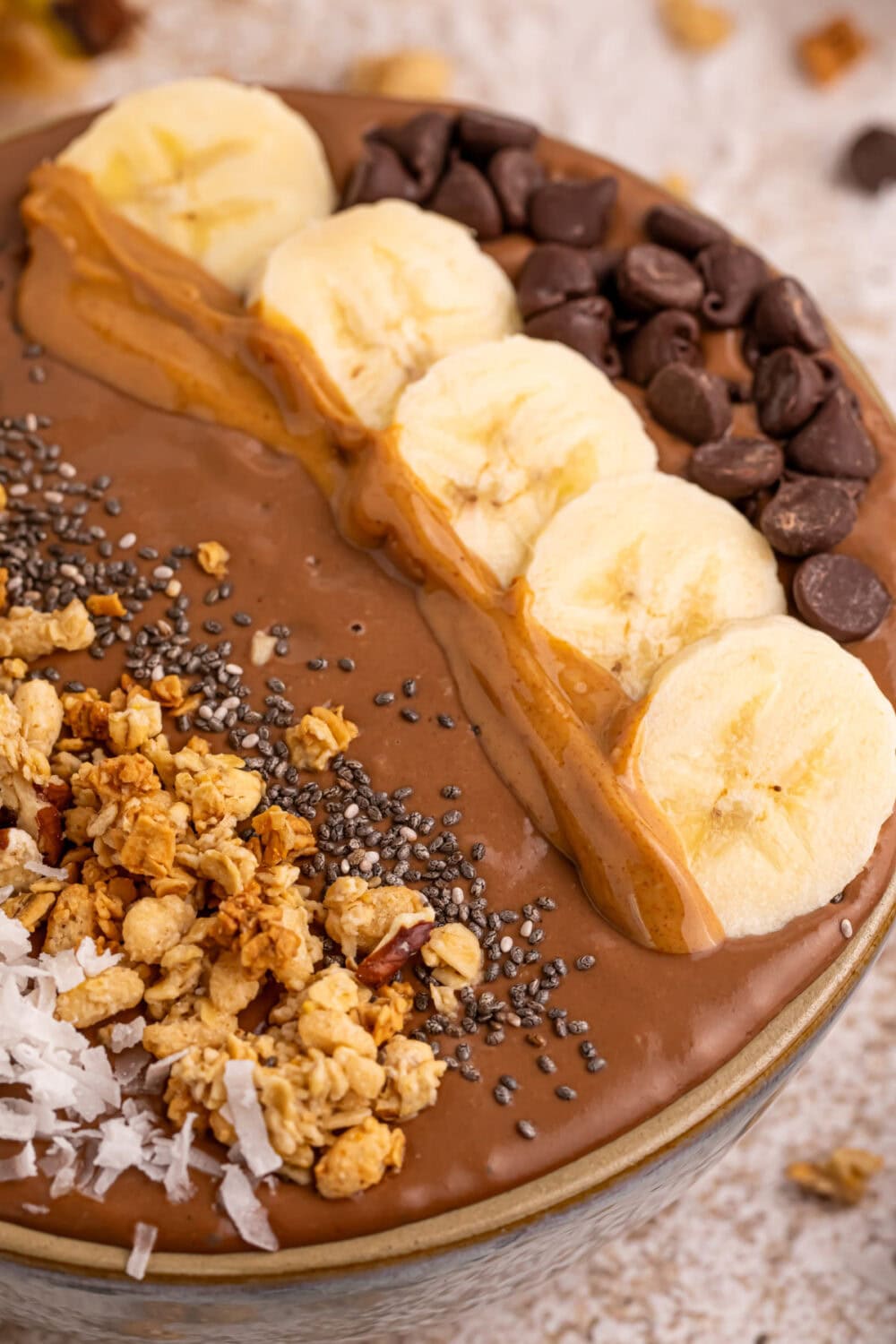 Chips, banana slices, and other toppings on top of a smoothie bowl. 